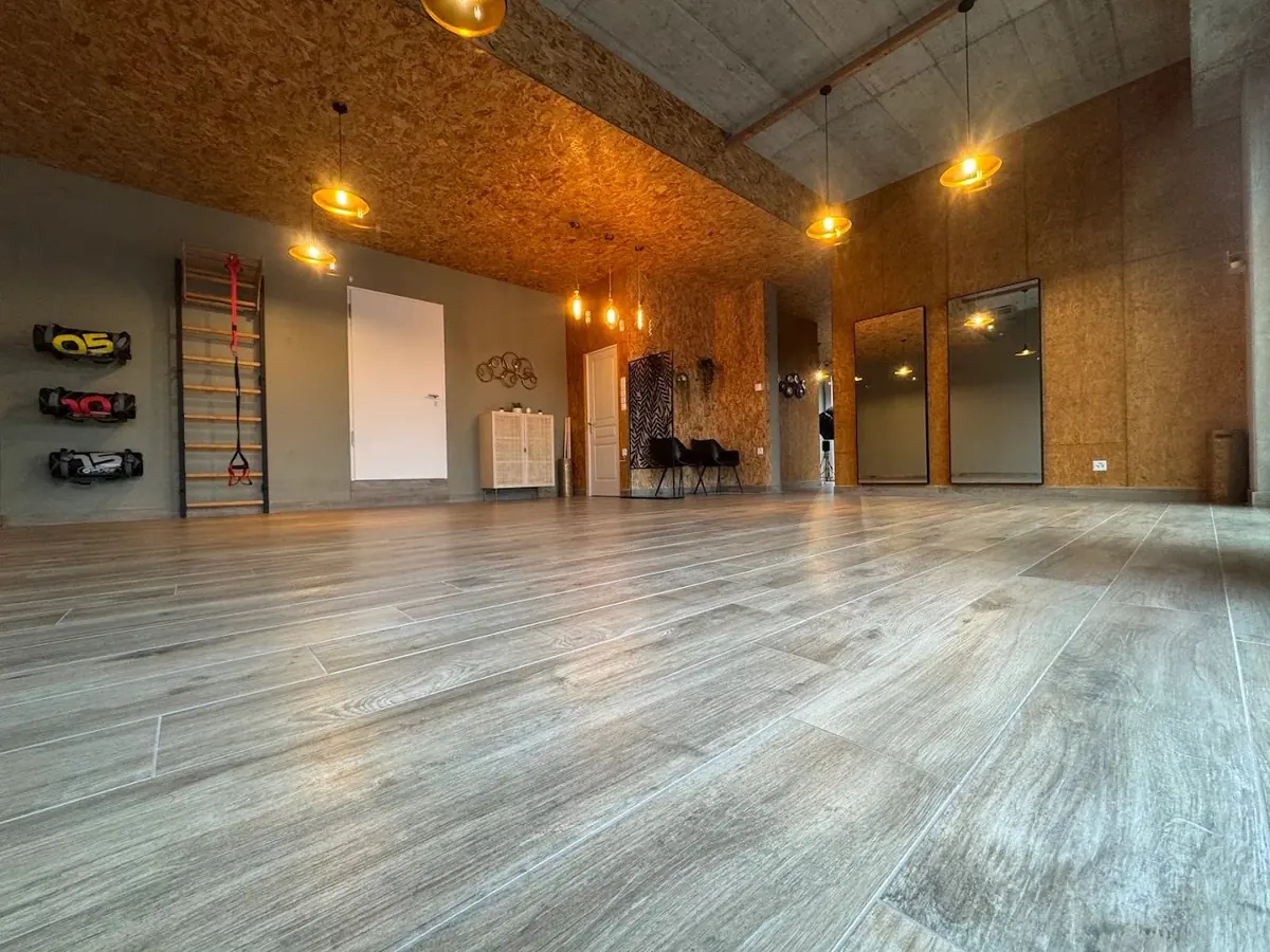 La grande salle du cabinet Physio Corner au Petit-Lancy : parquet, bois chaud et suspensions dorées