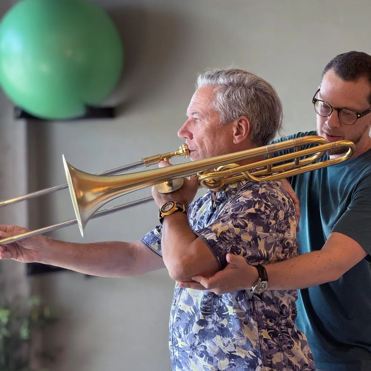 Sébastien guide l'épaule et le coude d'un tromboniste pendant qu'il joue